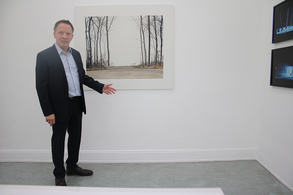 Der Galerist Lothar Albrecht vor einer Fotografie von Oliver Bloberg