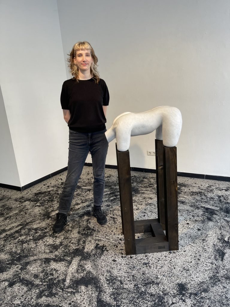 Anika Charlene Manthey in der Ausstellung „Der Mensch entmenschlicht den Menschen“ von Elena Artemenko. Der verschmutzte Boden ist Teil des künstlerischen Konzepts und verweist auf Spuren von Gewalt und Erinnerung. Foto: Edda Rössler