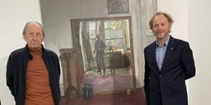 Ernst Hübner und James Lloyd (rechts) in der Frankfurter Galerie Hübner & Hübner vor dem zentralen Interieur der Ausstellung „Two Decades“. Das Spiegelbild zeigt den Maler in seinem Londoner Atelier, wo auch die Porträts der Galeristen entstanden. Foto: Edda Rössler