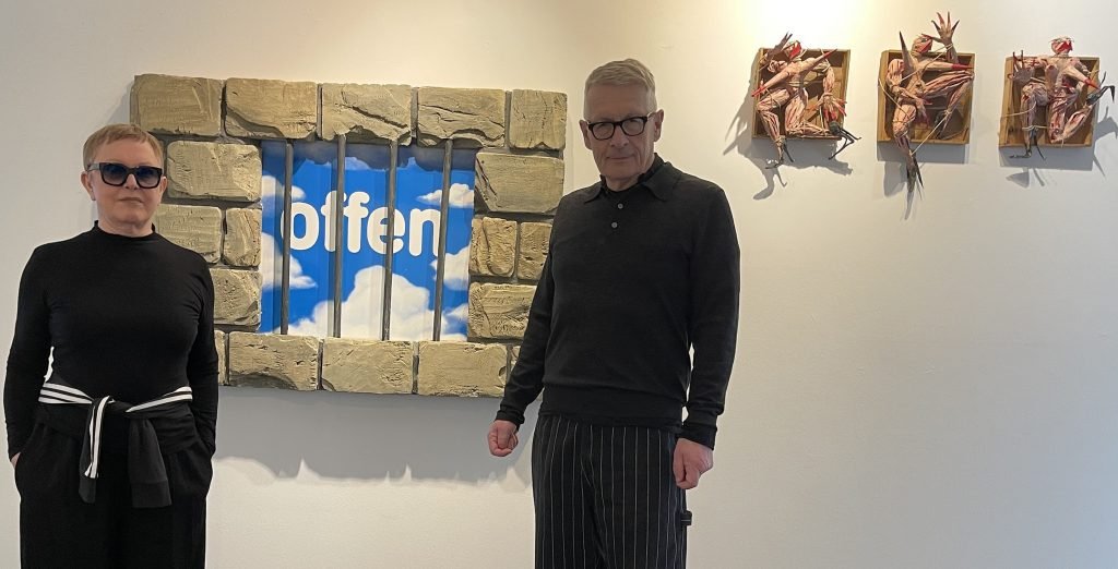 Ingrid und Andreas Honneth vor Gefängnisfenster mit Himmel „offen“ Himmel hinter Gittern: Das Wort „offen“ schwebt im Blau, gerahmt von steinernen Blöcken. Freiheit erscheint als Versprechen, das sich zugleich als Konstruktion entlarvt. Foto: Edda Rössler